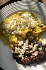 Mexican green chilaquiles with beans and fresh cheese