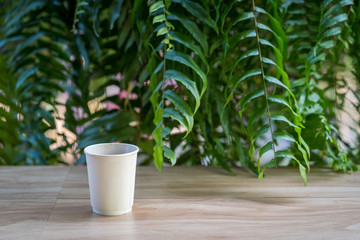 White paper cup coffee on wooden table.