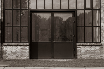An old industrial facade with a glass front and a door, door with glass windows, yellow brick,...