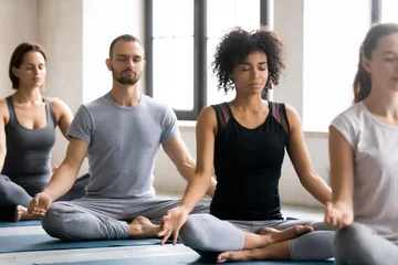 Poster Diverse young people meditating, sitting in Lotus pose, practicing yoga © fizkes