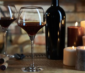 Glasses of red wine with candle lights and bottle