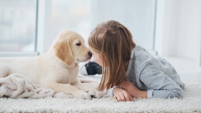 Smiling girl nose to nose with playful puppy in light room