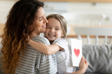 Loving daughter preparing card for mother congratulates with holiday