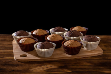 Cupcake. Tasty food cake. Chocolate muffins sprinkle with powdered sugar. Bakery products on black background. Black and white, light and shadow