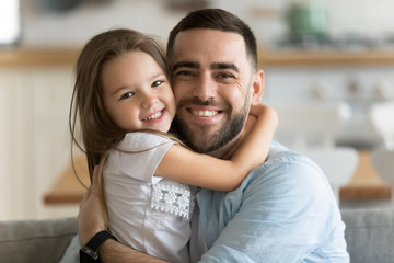 Lovely daughter strong embraces loving father smiling looking at camera