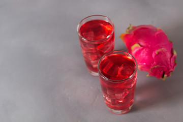 Glass of mango dragonfruit refresher drink on grey table with ice cubes. Copy space.