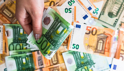 Hand giving money like bribe or tips isolated on banknotes background. EURO and USD currency...