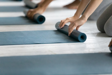 People folding yoga mat after working out in studio