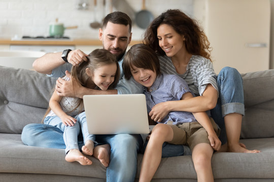 Family with kids spend time together using laptop websites