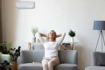 Calm elderly woman relax on couch breathe fresh air