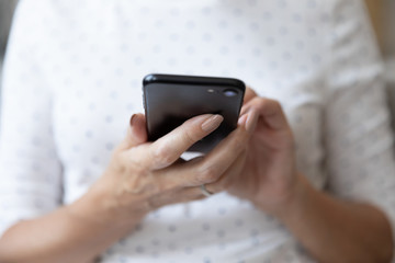 Close up of mature female using smartphone browsing internet
