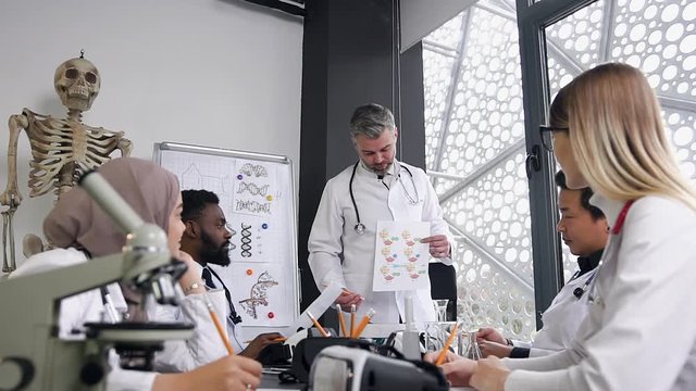 Attractive picture of high-skilled mixed race doctors which sitting in the hospital office and listening the report of their male doctor with gray hair