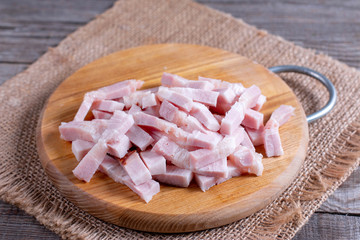 Sliced smoked bacon on a cutting board on a wooden background