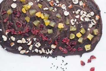 Homemade dark and light chocolate bar with dried cranberries, pears and hazelnuts, black sesame