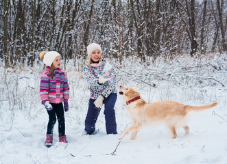 Fototapeta na wymiar Happy family playing with his pet on Christmas holidays in frozen forest