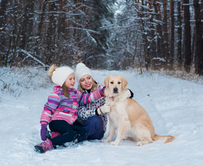 Fototapeta na wymiar Happy family playing with his pet on Christmas holidays in frozen forest