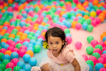 Fototapeta na wymiar Cute asian girl playing colorful plastic ball at playground.