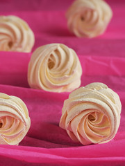 A freshly prepared delicious homemade apricot marshmallow (zephyr) located on a pink background. Vertical orientation. Selective focus on marshmallows.