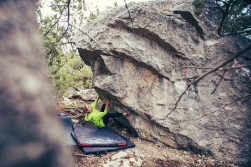 Woman climbs boulder.