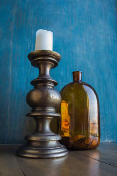 Big Brown Glass Jar With Coins And Massive Candleholder With White Candle On It On Blue Shabby Wall Background, Concept Of Savings, Trading, Savings Or Electricity Economy