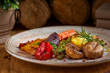 Grilled green vegetables - bell pepper, onion, potatoes, markov and rosemary on a plate. On a wooden table close-up