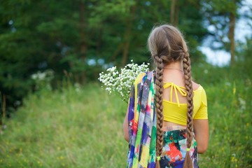 A girl of European appearance in a traditional Indian Sari holding a bouquet of white flowers in a clearing