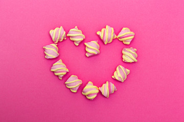 Zephyr lined in a heart shape on a white background. Flat lay. Top view. Pink sweet homemade zephyr or marshmallow. Colorful meringues on white. top view dessert image.
