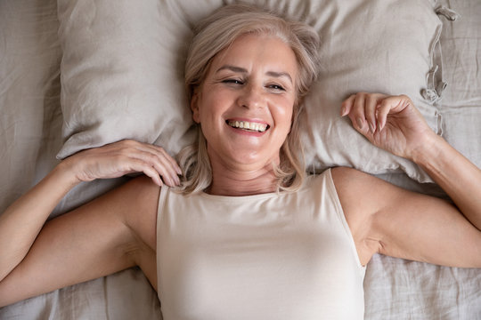 Top view of smiling senior woman wake up feeling positive