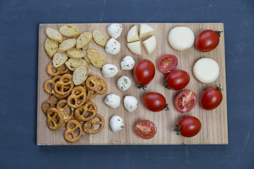  snacks, cheese, vegetables lie on a wooden board on a blue background
