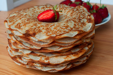 stack of freshly prepared traditional pancakes with strawberries