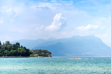 Panoramic view against bright sun rays above the rocks on beautiful Garda lake shore in Riva del...