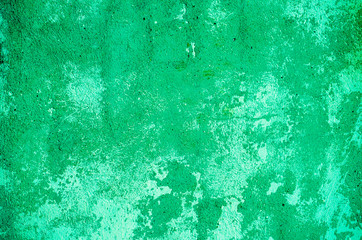 Fragment of old house wall close-up. Green background. Peeling plaster on concrete surface. tinted green. Cracks in paint. Copy space. Place for text. Selective focus image.