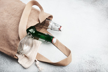Reusable glass bottles and jars in burlap bag. Sustainable lifestyle. Zero waste grocery shopping...