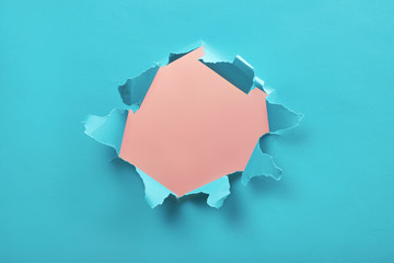 Torn hole in blue paper, ripped edges