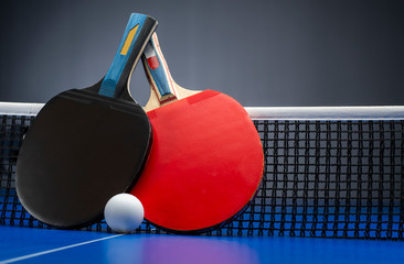 Ping pong rackets and balls on a blue table with net. - obrazy, fototapety, plakaty