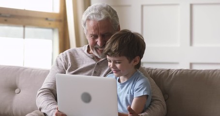 Happy old grandfather and grandson using laptop video calling - Powered by Adobe