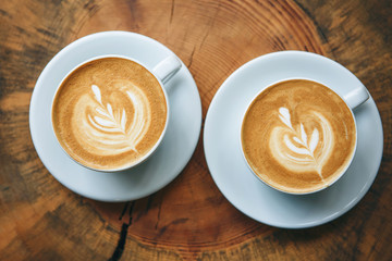 Two cups of aromatic coffee cappuccino or latte on a wooden table. Concept of meeting or relaxing. Tasty morning drinks.