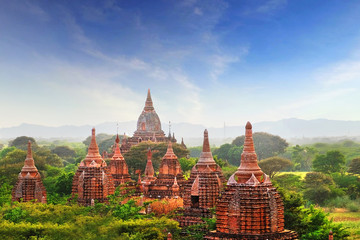Blue sky above temples surrounded by green vegetation in old Bagan, Myanmar.