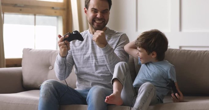 Overjoyed dad and child son gamers winners playing winning videogame