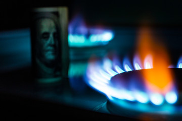 Burning bill of hundred dollars on a gas burner flame, expensive natural gas, the front and...