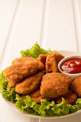 Chicken nuggets with ketchup and lettuce on a white wooden background with copy space