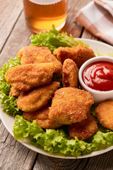 Close up of chicken nuggets with ketchup and lettuce on a wooden background