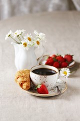 Breakfast. Croissant and strawberry. And black coffee, a bouquet of flowers. Fresh strawberries. 