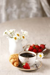 Breakfast. Croissant and strawberry. And black coffee, a bouquet of flowers. Fresh strawberries. 