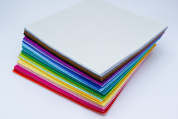A stack of felt pieces arranged in perfect rainbow colors from white, black, brown, purple, blue, green, yellow, orange and red. Isolated. Copy space