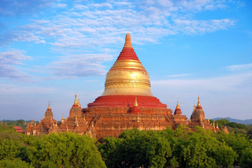 Blue sky above temples surrounded by green vegetation in old Bagan, Myanmar.