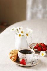 Breakfast. Croissant and strawberry. And black coffee, a bouquet of flowers. Fresh strawberries. 