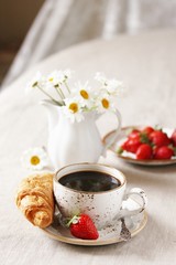Breakfast. Croissant and strawberry. And black coffee, a bouquet of flowers. Fresh strawberries. 