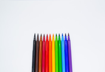 Multi-colored markers with a brush tip, arranged according to the colors of the rainbow. White background. The concept of creativity, drawing, bright world, back to school, study. Copy space