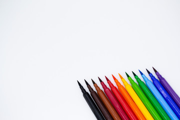 Close up of Multicolored markers with a brush tip, arranged according to  colors of the rainbow. White background. The concept of creativity, drawing, bright world, back to school, study. Copy space